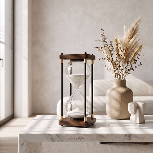 Ampulheta de areia branca sobre aparador de mármore com vaso de cerâmica, decoração de sala Casa Vértice.