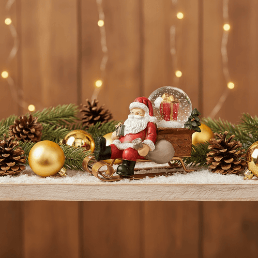 estatueta natalina Papai Noel no trenó em composição com pinhas e bolas douradas