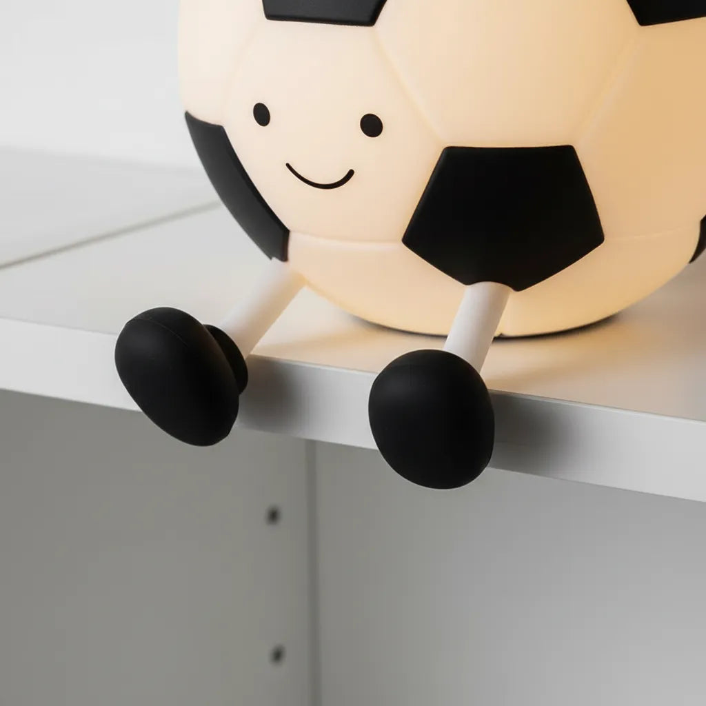 Criança segurando luminária de futebol macia e segura com luz LED quente.