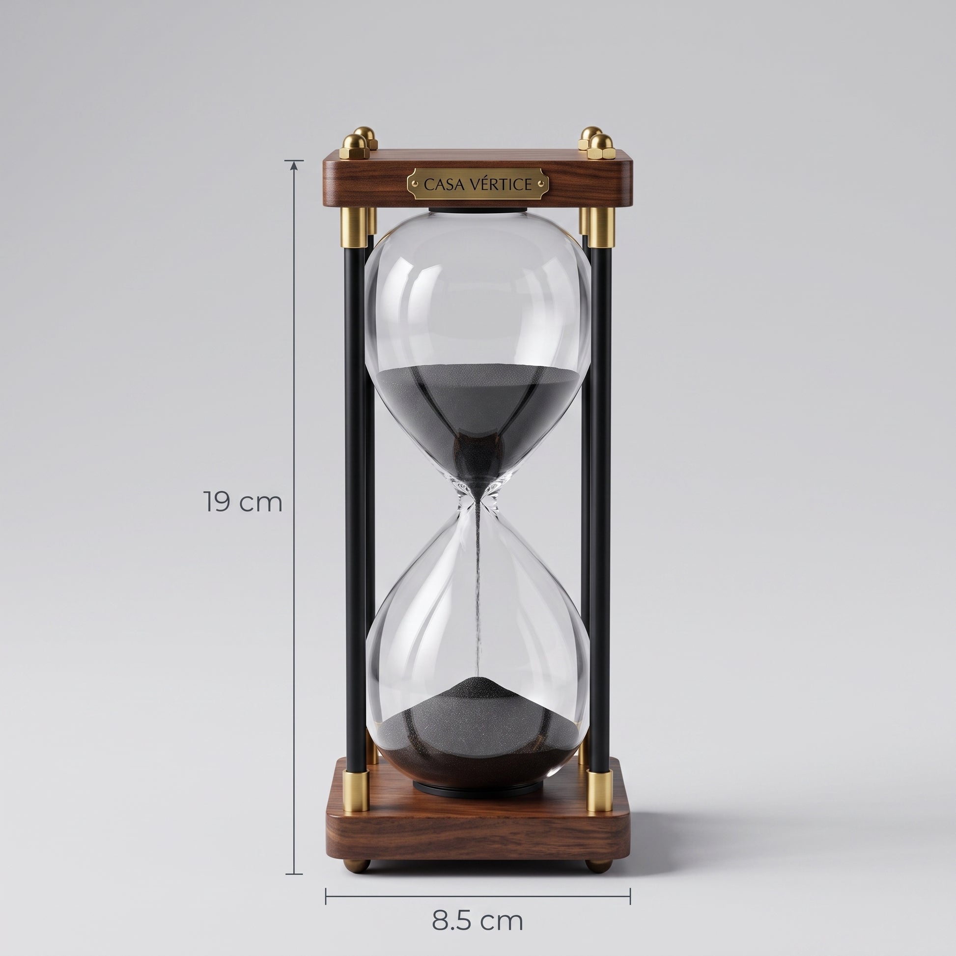 Ampulheta decorativa em fundo neutro com indicação técnica de medidas de 19 cm de altura por 8.5 cm de largura da base, placa com logo Casa Vértice.