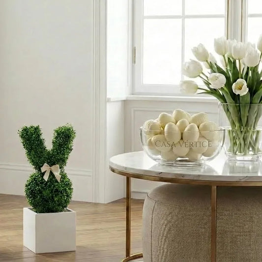 Decoração de Páscoa sofisticada com coelho de grama artificial e vaso de tulipas brancas em mesa de mármore.