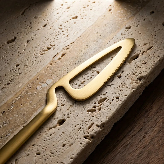 Detalhe macro da lâmina da faca de jantar dourada de 27cm, destacando o corte de precisão Casa Vértice.