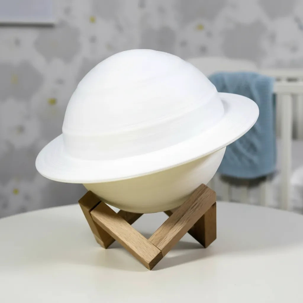 Luminária Saturno 3D desligada sobre base de madeira em quarto infantil moderno.